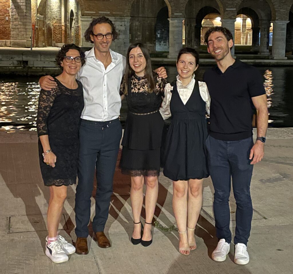 An image of the Willows Neurology Team stood together and smiling. There is an old brick building and a canal in the background